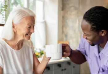 Elderly woman having coffee with a volunteer