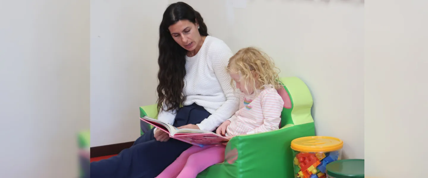Kids Club teacher reading with a child. 
