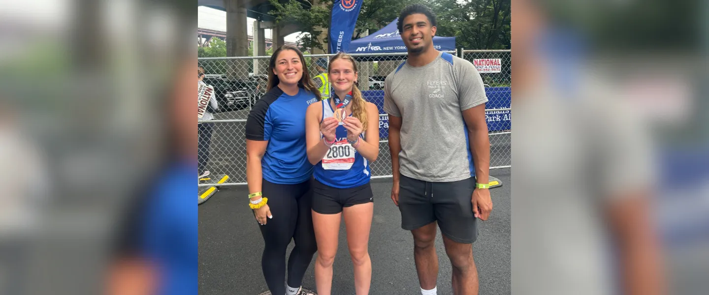 Flyers coaches with an athlete and her medal