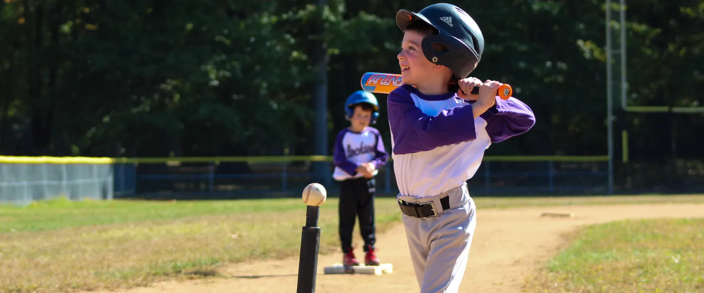 T-Ball athlete smiling and getting ready to swing his bat