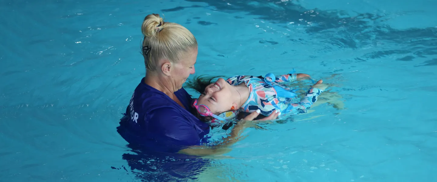 Swim instructor helping a student learn how to float on their back