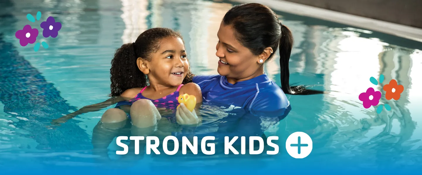 Young child smiling while being held by a swim instructor in a YMCA pool during a swim lesson, with the text “Strong Kids+” displayed over the water.