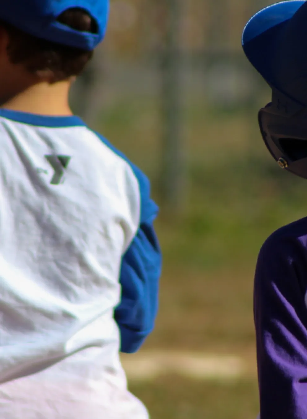 two T-Ball players. one with a helmet on base, the other playing the field.