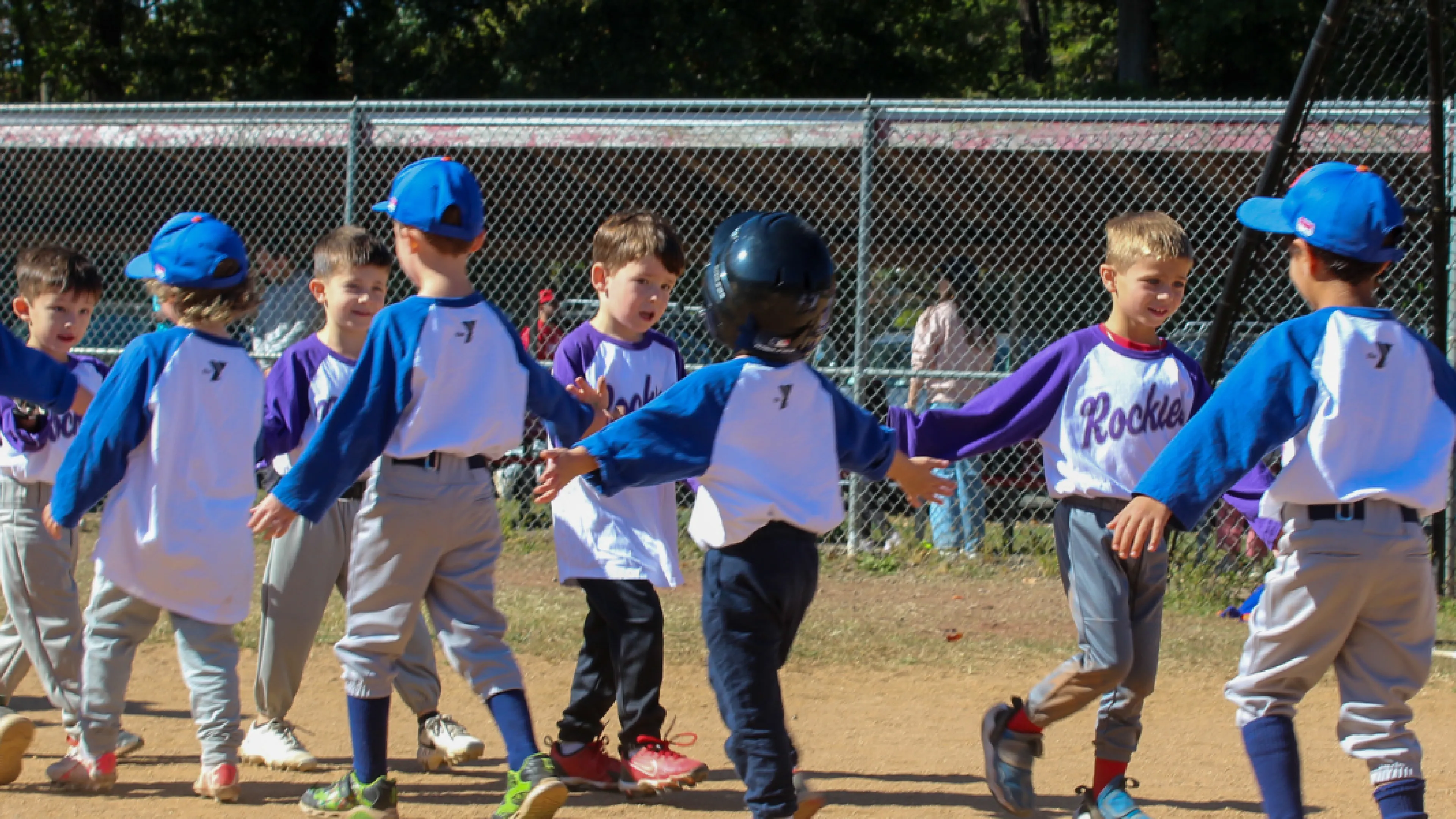 Group of T-Ball players high-five each other after a game.