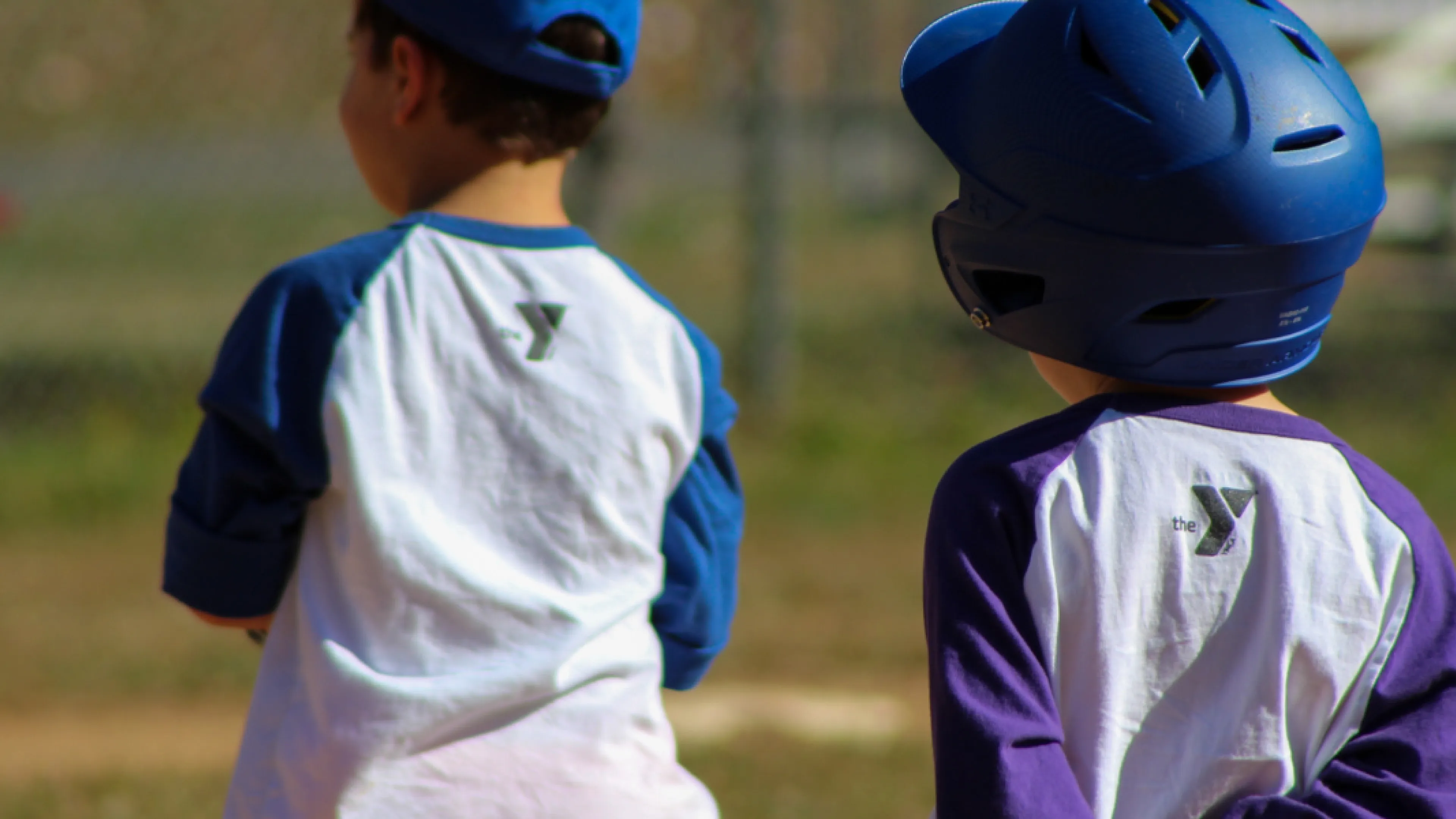two T-Ball players. one with a helmet on base, the other playing the field.
