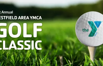 A close-up of a golf ball with the YMCA logo resting on a tee in bright green grass, with text on the left reading "21st Annual Westfield Area YMCA Golf Classic."