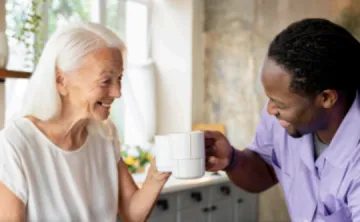 Elderly woman having coffee with a volunteer